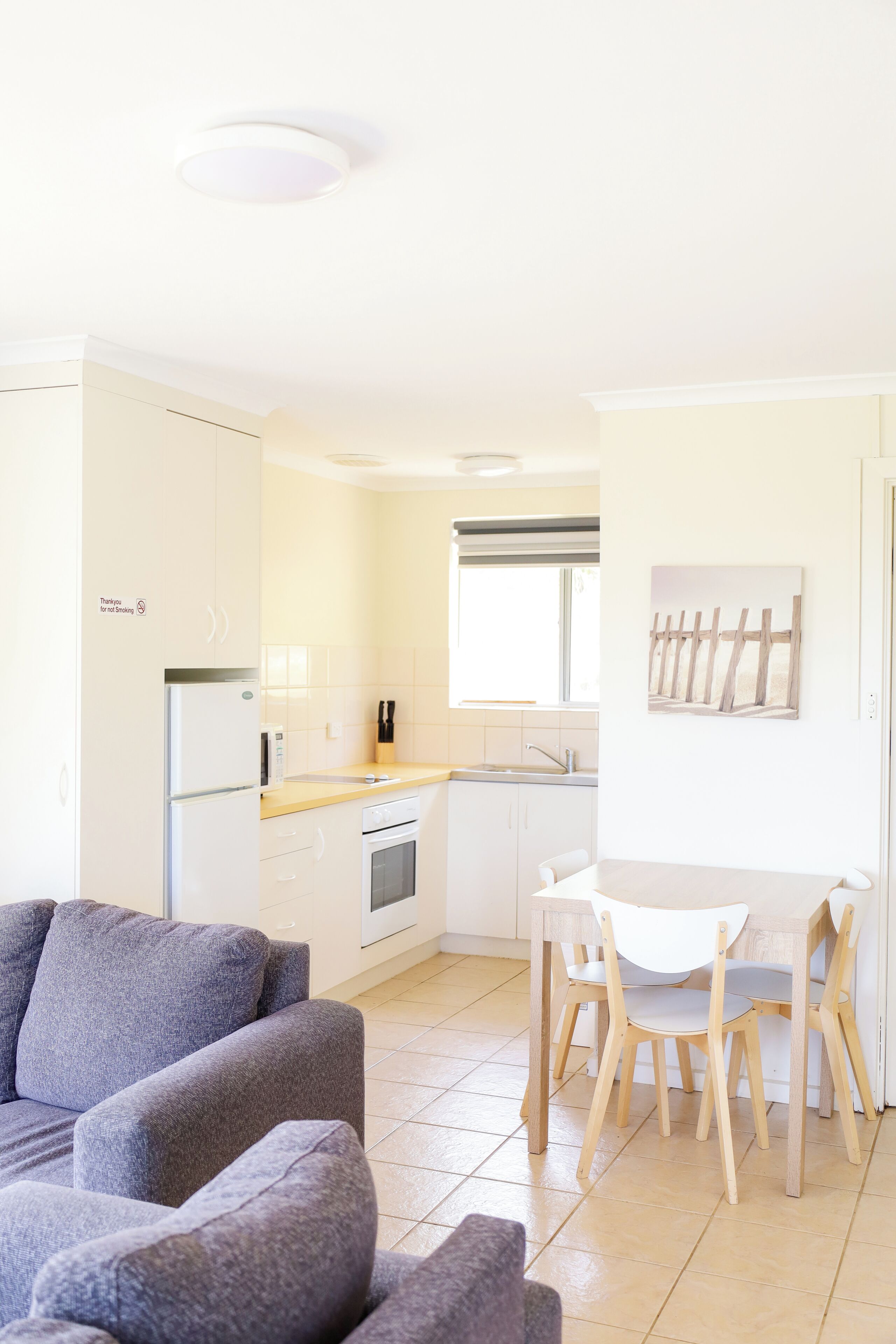 A modern kitchen with white cabinets, a refrigerator, and a dining area with a table and chairs.