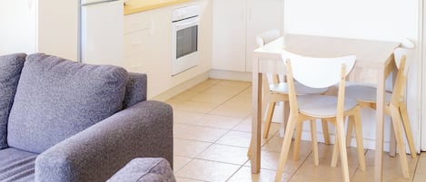 A modern kitchen with white cabinets, a refrigerator, and a dining area with a table and chairs.