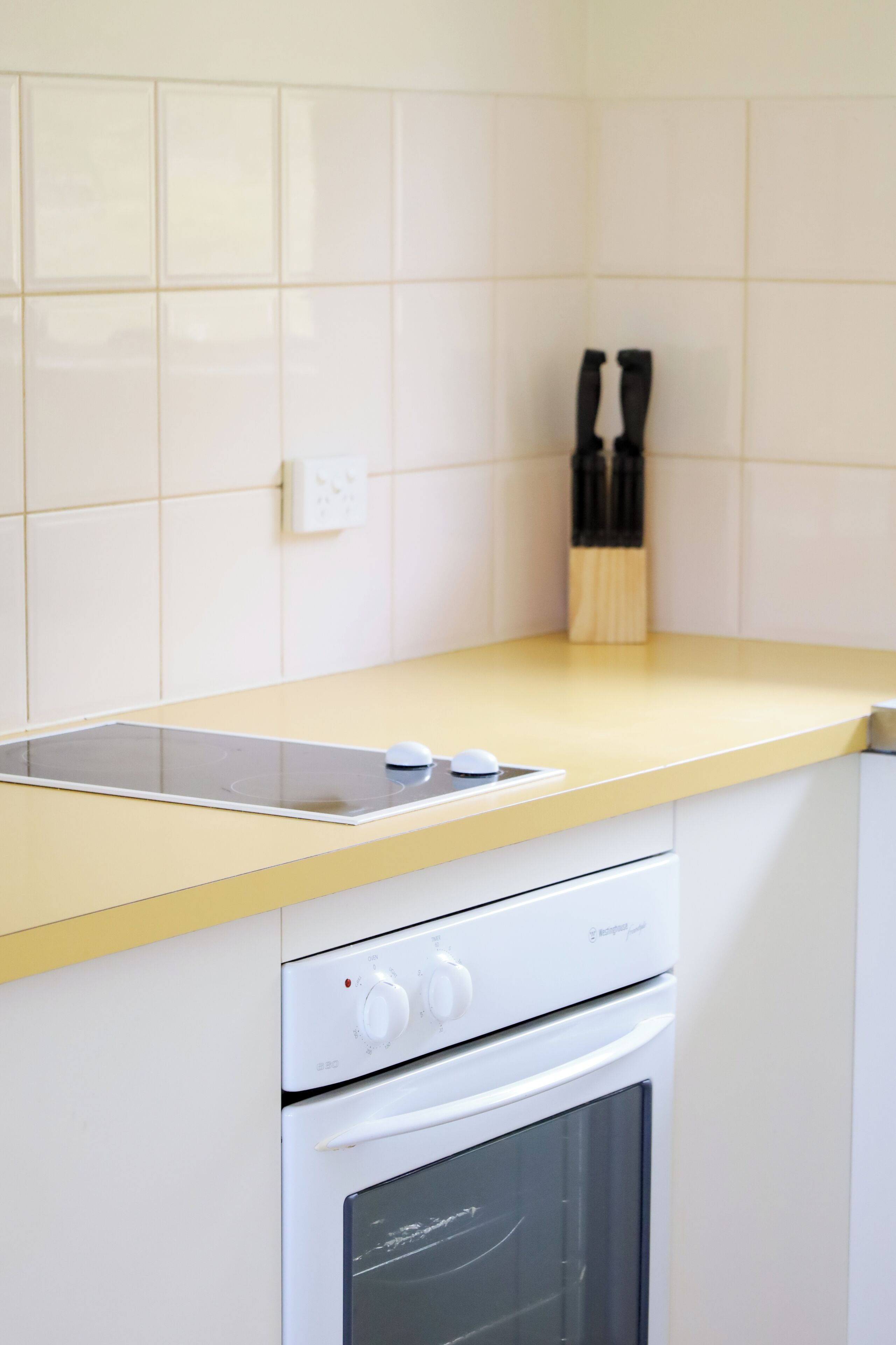 Une cuisine avec un plan de travail jaune, un four encastré et un porte-couteaux fixé au mur.