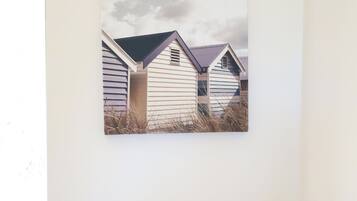 A bedroom with a bed, a pillow, and a wall-mounted picture of beach huts.