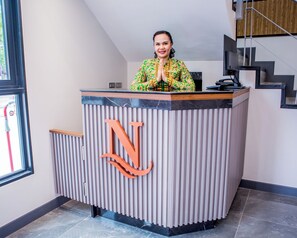 En receptionsdisk med en stor logotyp i form av bokstaven ”N”, en person som står bakom disken och en trappa till höger.