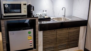 A compact kitchen with a microwave, refrigerator, sink, and coffee maker. - Nouriva Place Bangkok (Bangkok)