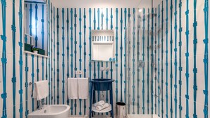 A bathroom with a white bathtub, a white sink, a blue vanity, and a glass shower enclosure.