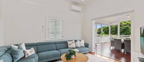 A modern living room with a sectional sofa, a round wooden coffee table, and a view of an outdoor patio area.