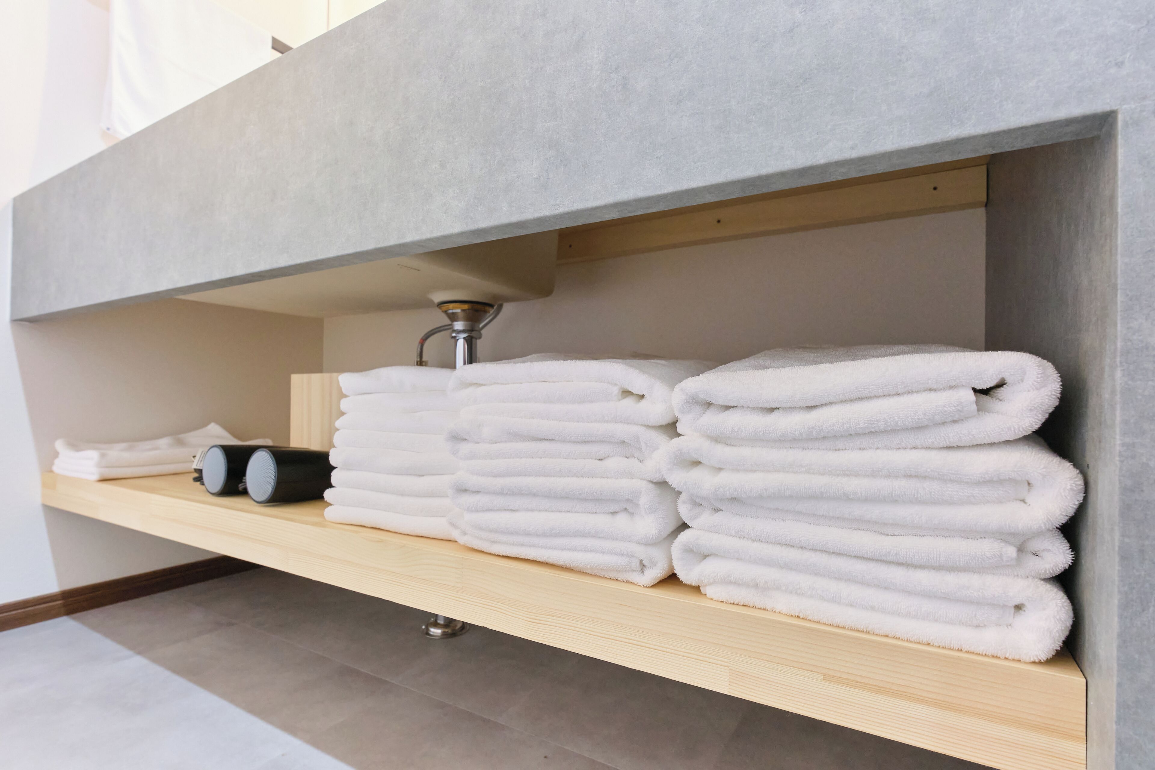 A bathroom with a towel rack holding neatly folded towels and a bottle.