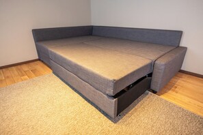 A grey sofa with a storage compartment, a beige carpet, and wooden flooring.