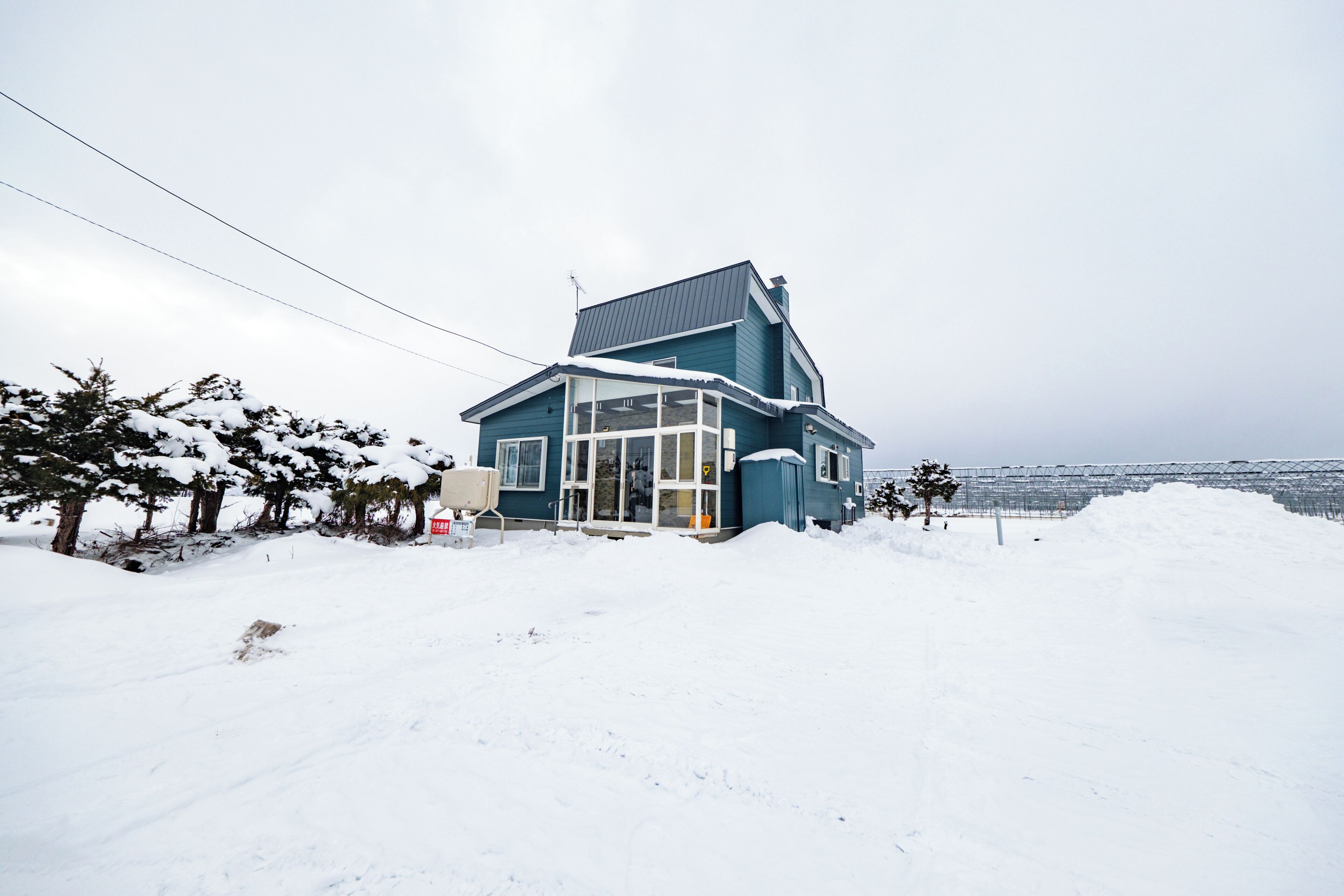 Una casa con techo inclinado, amplias ventanas y un paisaje cubierto de nieve.