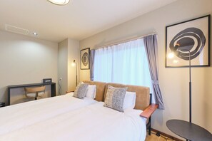 Habitación de hotel con una cama grande, un escritorio, una silla y una mesita.