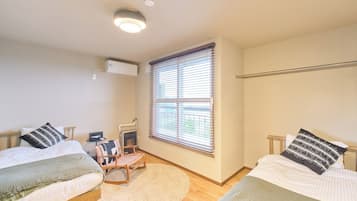 A bedroom with two beds, a heater, a window with blinds, and a ceiling light.