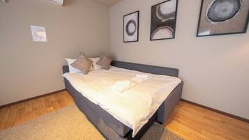 A bedroom with a bed, pillows, a rug, and three framed pictures on the wall.