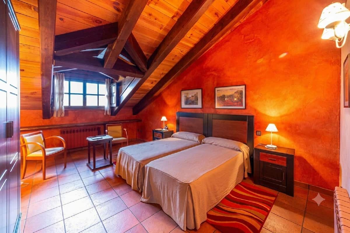 Una habitación acogedora con dos camas, un escritorio, una silla y un ventanal.