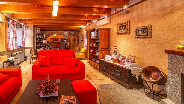 A cozy living room with a red sofa, a coffee table with a floral centerpiece, and a fireplace with a bowl.