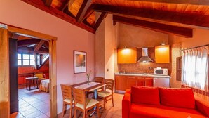 A cozy interior with a dining area, a kitchen, and a red sofa.