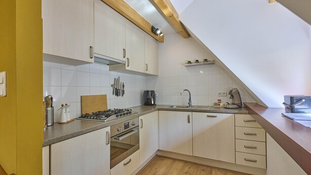 A modern kitchen with white cabinets, a gas stove, an oven, and a sink.