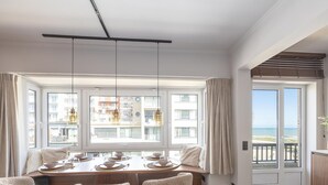Ein Essbereich mit großem Fenster, einem Tisch für vier Personen und Blick aufs Meer.
