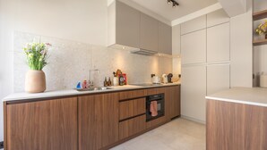 Eine moderne Küche mit Holzschränken, einem eingebauten Ofen und einer Arbeitsplatte mit verschiedenen Geräten.