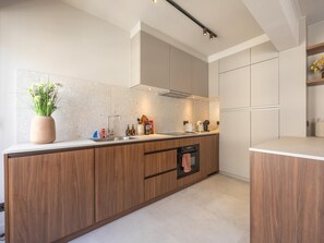 Eine moderne Küche mit Holzschränken, einem eingebauten Ofen und einer Arbeitsplatte mit verschiedenen Geräten.
