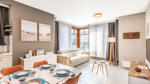 Une chambre d’hôtel moderne dotée d’un coin repas, d’un canapé et offrant une vue sur la ville.