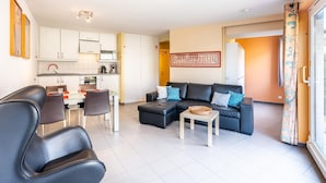 Una sala de estar moderna con sofá, sillas, una mesa de comedor y una zona de cocina.