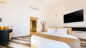 Ein Hotelzimmer mit einem großen Bett, einem Schreibtisch mit einem Laptop, einem Flachbildfernseher und moderner Einrichtung.