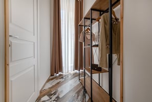 Un couloir avec un plancher en bois, un portant à vêtements et une porte.