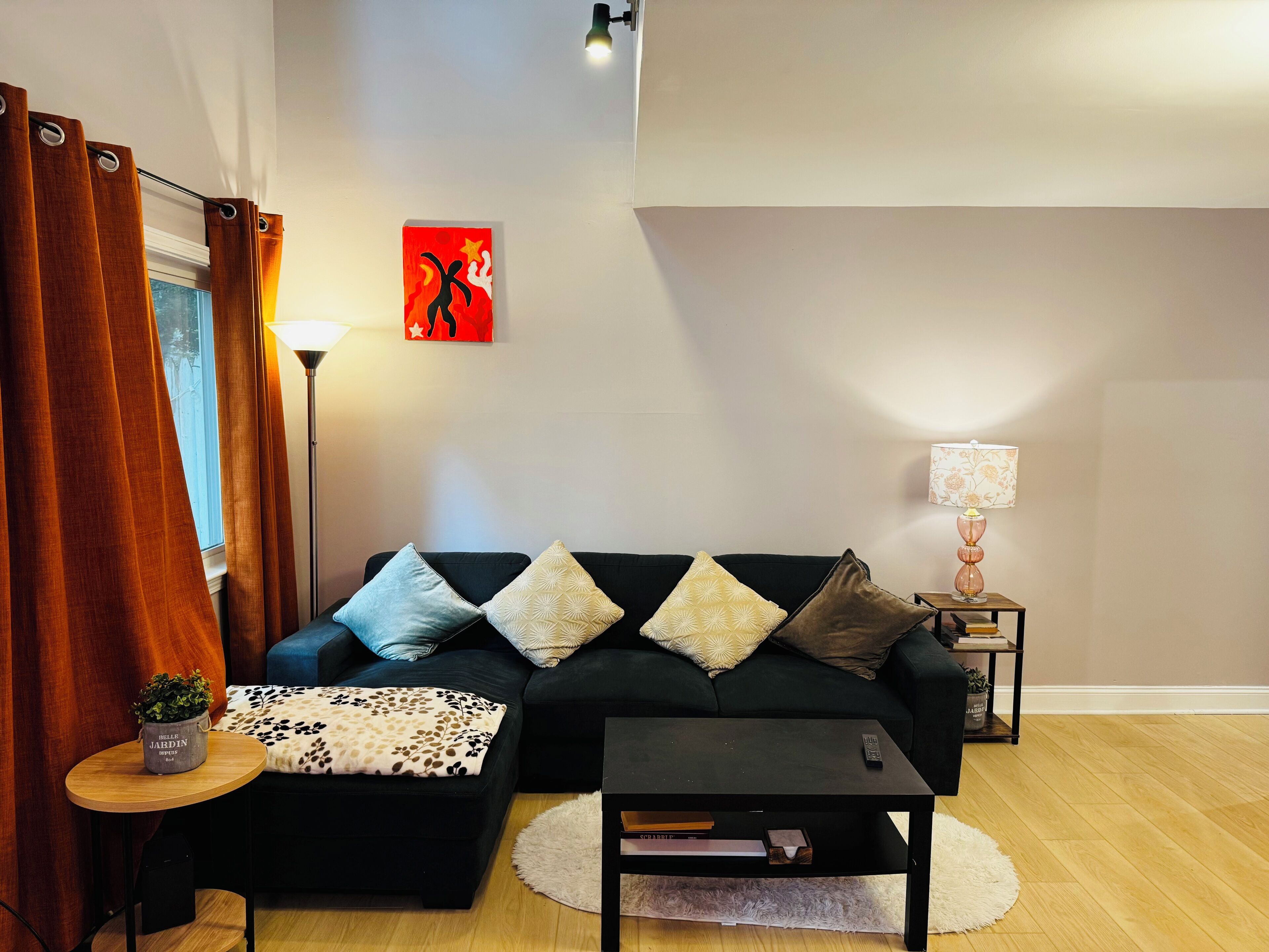 A living room with a sofa, a coffee table, a lamp, and a painting on the wall.