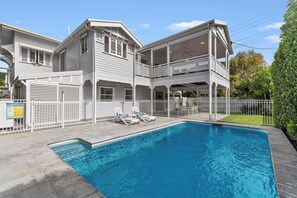 Ein zweistöckiges Gebäude mit Pool und überdachter Terrasse.
