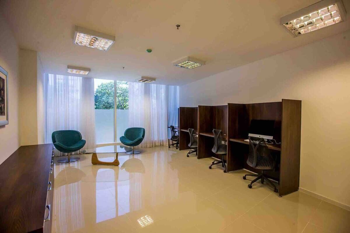 A modern office space with a large desk, two chairs, a TV, and a bookshelf.