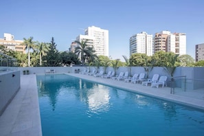 A swimming pool with lounge chairs and a clear view of surrounding buildings. - Corporate Stays The Tower (Asunción)