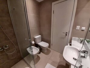 A modern bathroom with a glass shower enclosure, a toilet, a bidet, and a sink. - Corporate Stays The Tower (Asunción)