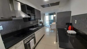 A modern kitchen with black countertops, stainless steel appliances, and a view to the living area. - Corporate Stays The Tower (Asunción)