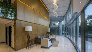 A modern lobby with a reception desk, seating area, and large windows. - Corporate Stays The Tower (Asunción)
