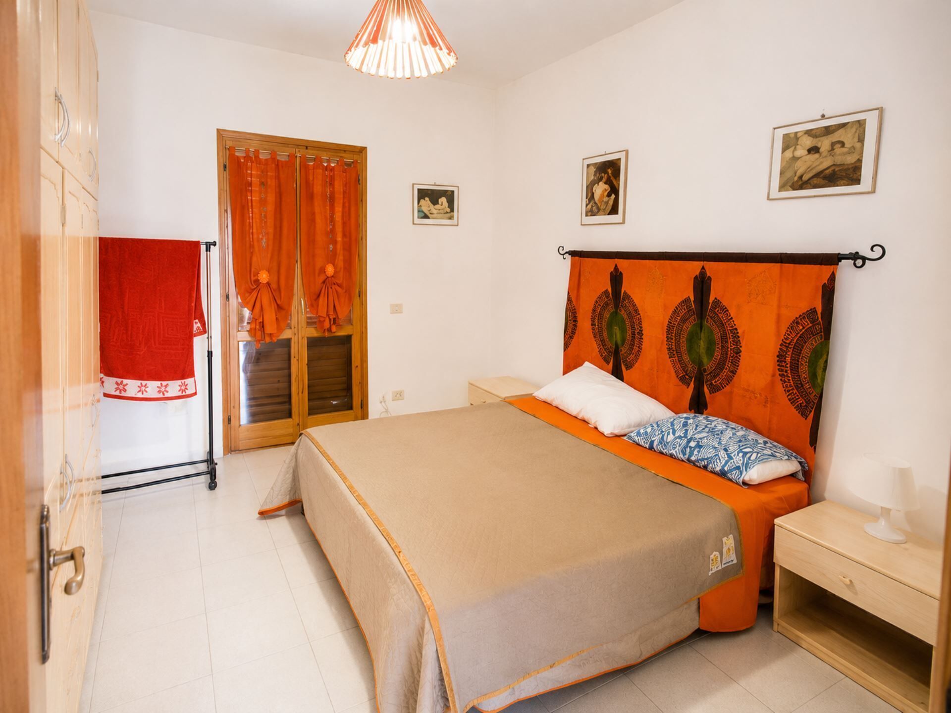 A bedroom with a bed, a nightstand, a window with curtains, and a door.