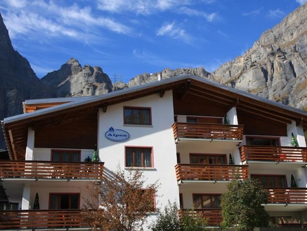 A multi-story building with balconies, a sign reading 'Alpen,' and a mountainous backdrop. - Alpen Leukerbad # 2-bed apartment, Dusche, WC by Interhome (Leukerbad)