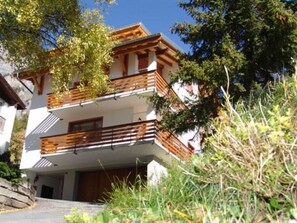 A multi-story building with balconies, a staircase, and a surrounding natural landscape. - Alpen Leukerbad # 2-bed apartment, Dusche, WC by Interhome (Leukerbad)
