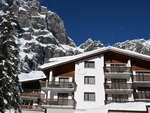 A multi-story hotel with balconies, a mountain backdrop, and snow-covered surroundings. - Alpen Leukerbad # 2-bed apartment, Dusche, WC by Interhome (Leukerbad)