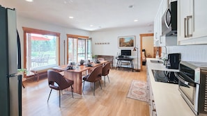 A modern kitchen with a dining area, wooden flooring, and a view through large windows. - Log Style Home with Hot Tub on the Golf Course! (Radium Hot Springs)