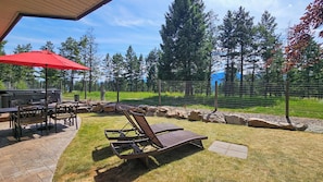 Eine Terrasse mit Gartenmöbeln, einem Grill und Blick auf eine bewaldete Landschaft.