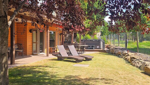 Una cabaña de madera con un patio, mobiliario exterior y zona de barbacoa.