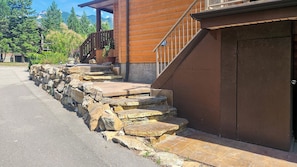 A stone staircase leading to a wooden building with a metal railing and a door. - Log Style Home with Hot Tub on the Golf Course! (Radium Hot Springs)