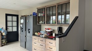 Una cocina con refrigerador, armarios y cafetera.