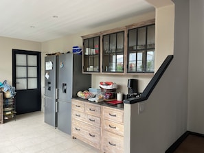 Eine Küche mit Kühlschrank, Schränken und einer Kaffeemaschine.