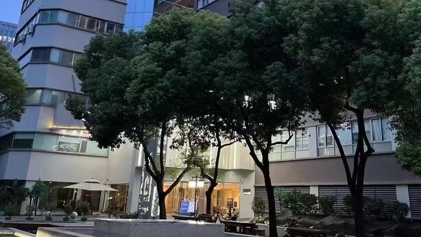 A modern building with multiple floors, a prominent antenna, and a well-maintained lawn area with trees. - Crystal Orange Hangzhou Zhejiang Univ. (Hangzhou)