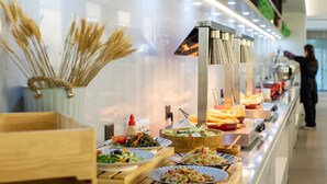 A buffet with various dishes, a person in the background, and a modern interior design. - Crystal Orange Hangzhou Zhejiang Univ. (Hangzhou)