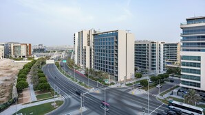 A modern urban intersection with high-rise buildings, a multi-lane road, and a pedestrian walkway. - Bloomfields 2BR in Lamar Raha Beach (Abu Dhabi)
