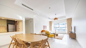 A modern living room with a dining table, chairs, a sofa, and a TV. - Bloomfields 2BR in Lamar Raha Beach (Abu Dhabi)