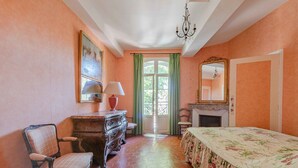 Una habitació amb un llit, una cadira, un taulell, un mirall i una llar de foc.