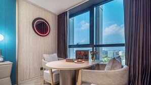 Una habitación moderna con una mesa redonda, dos sillas, un espejo circular y un ventanal con cortinas.