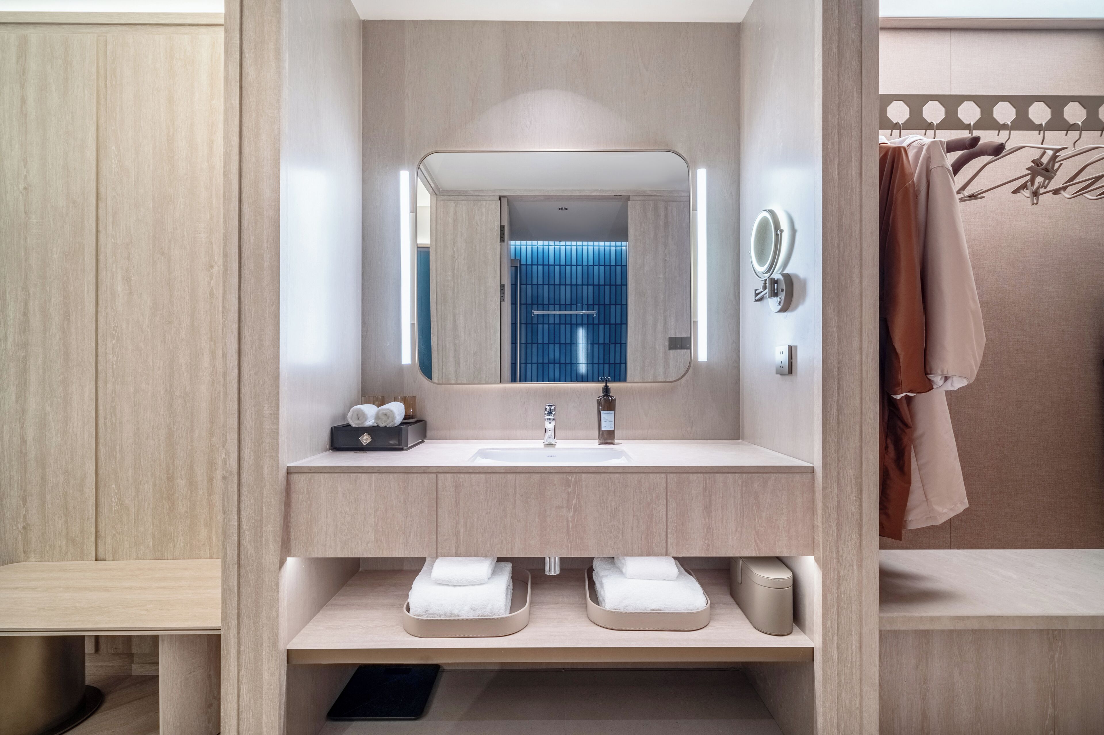 Un baño moderno con un espejo grande, un lavamanos y dos toalleros.