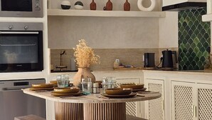 Una cucina moderna con isola centrale, illuminazione a sospensione e vasi decorativi.